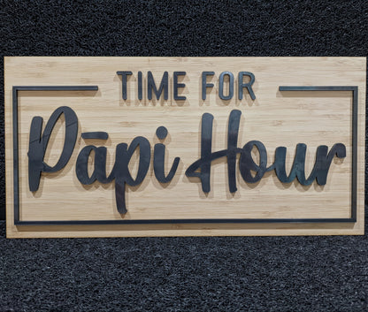 A rectangular wooden sign with the words 'TIME FOR Papi Hour' in raised dark lettering, displayed against a dark textured background.