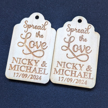 Two wooden christening gift tags with 'Spread the Love' and personalized names on a blue background