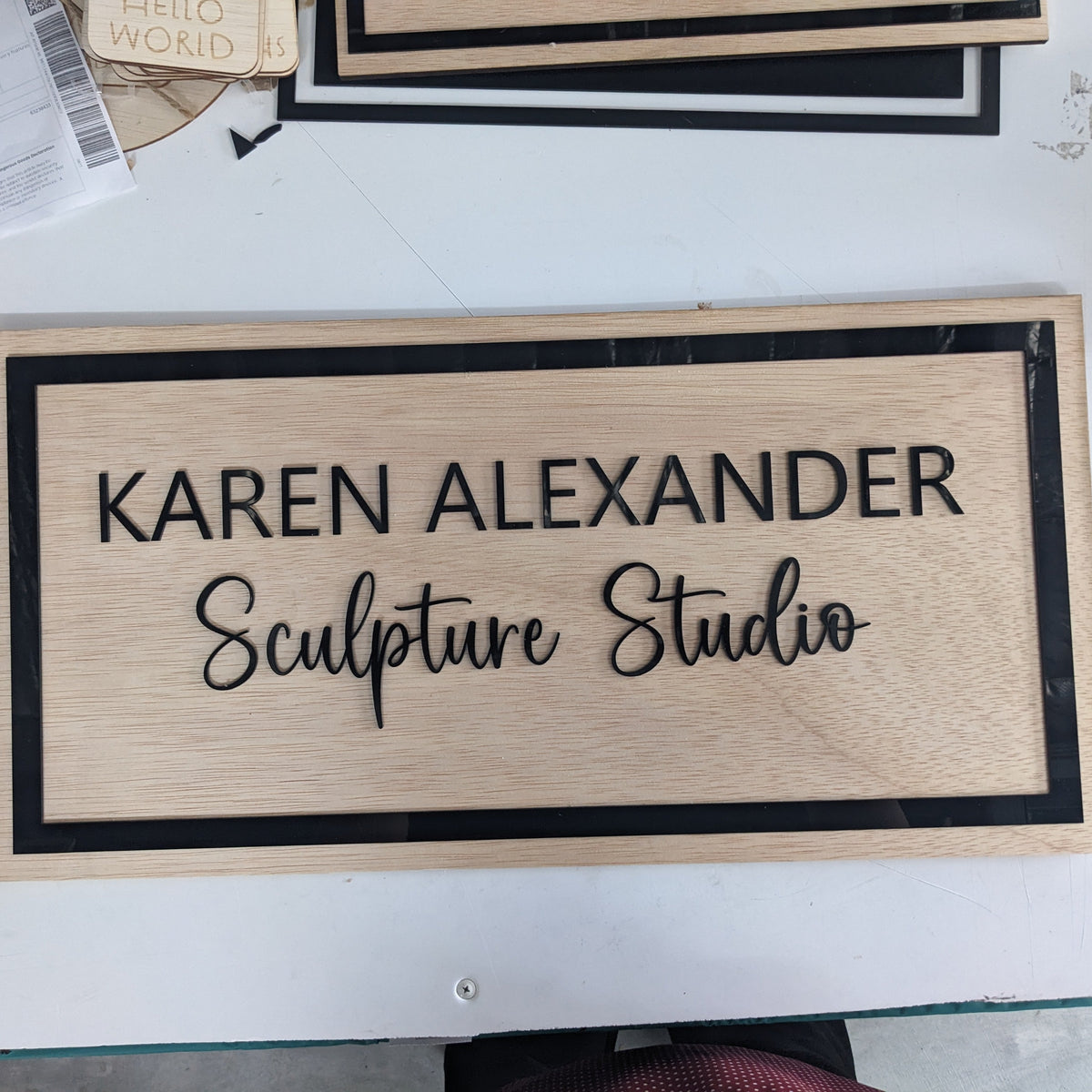 Business name Karen Sculpture studio  wooden sign with black acrylic on a white background 