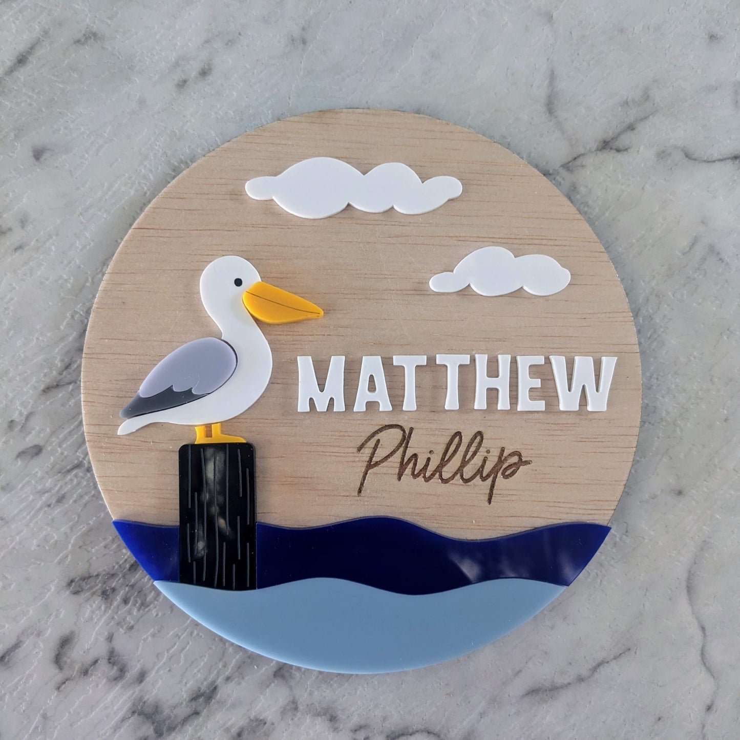 Round wooden sign with a pelican illustration personalised for nursery