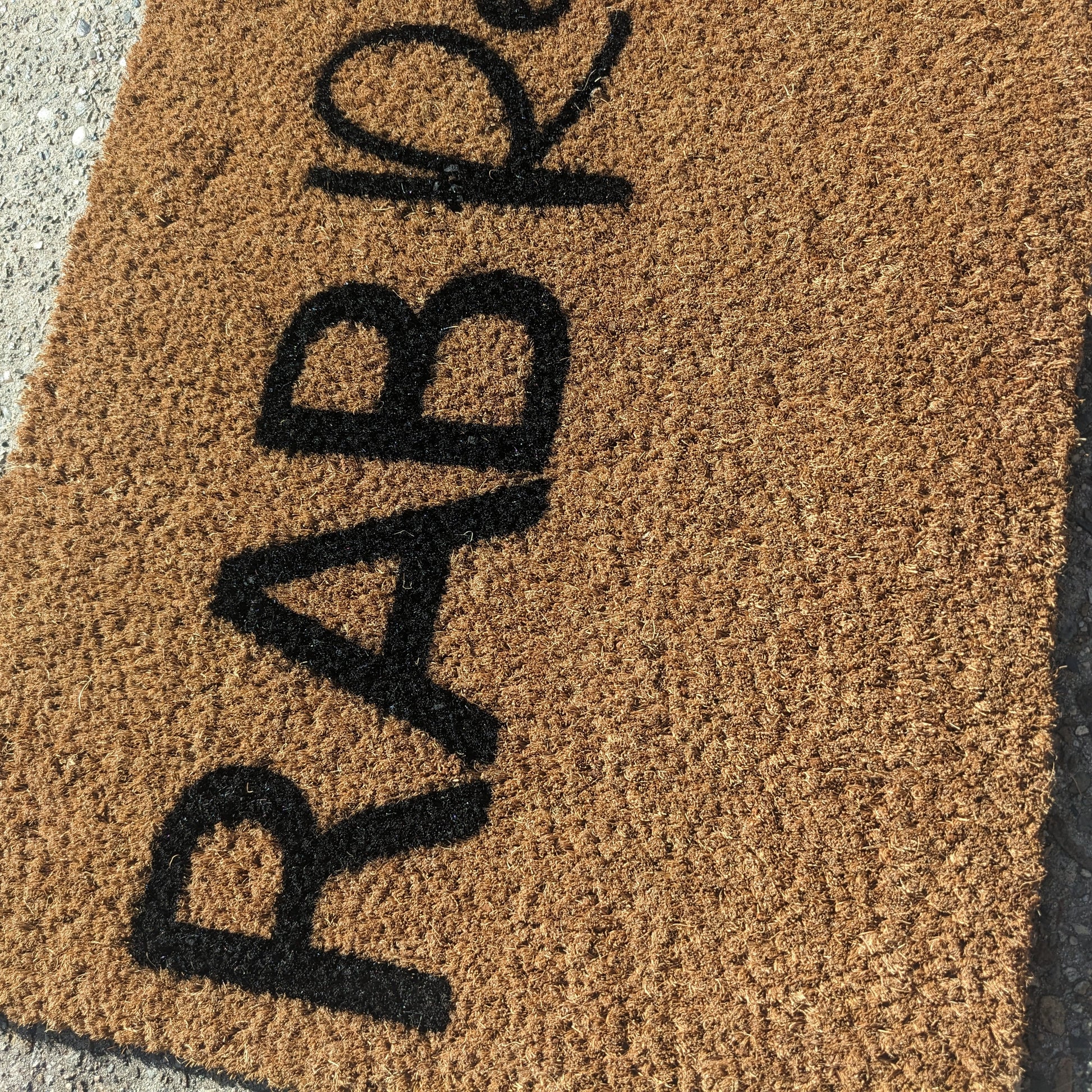 Doormat with 'RAB Resort' printed on it on a concrete surface
