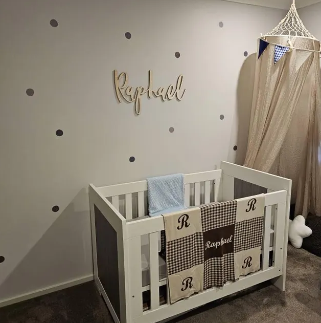 Nursery room with a crib, decorative name on the wall, and baby blankets.