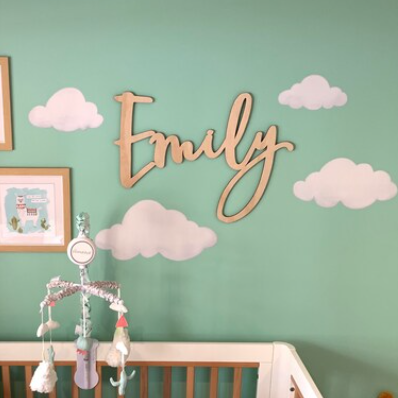 Nursery room with a crib, name decor, and wall art on a green wall.