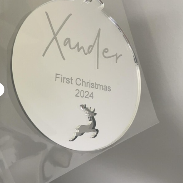 Round silver ornament with 'Xander' and 'First Christmas 2024' engraved, on a light gray background.