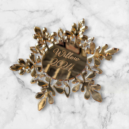 Gold snowflake ornament with 'Willow 2024' engraving on a marble background