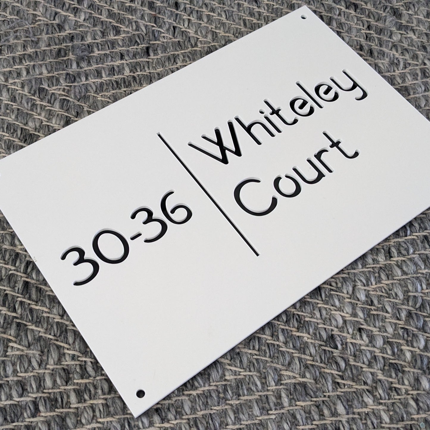 White address sign with black text on a textured gray background