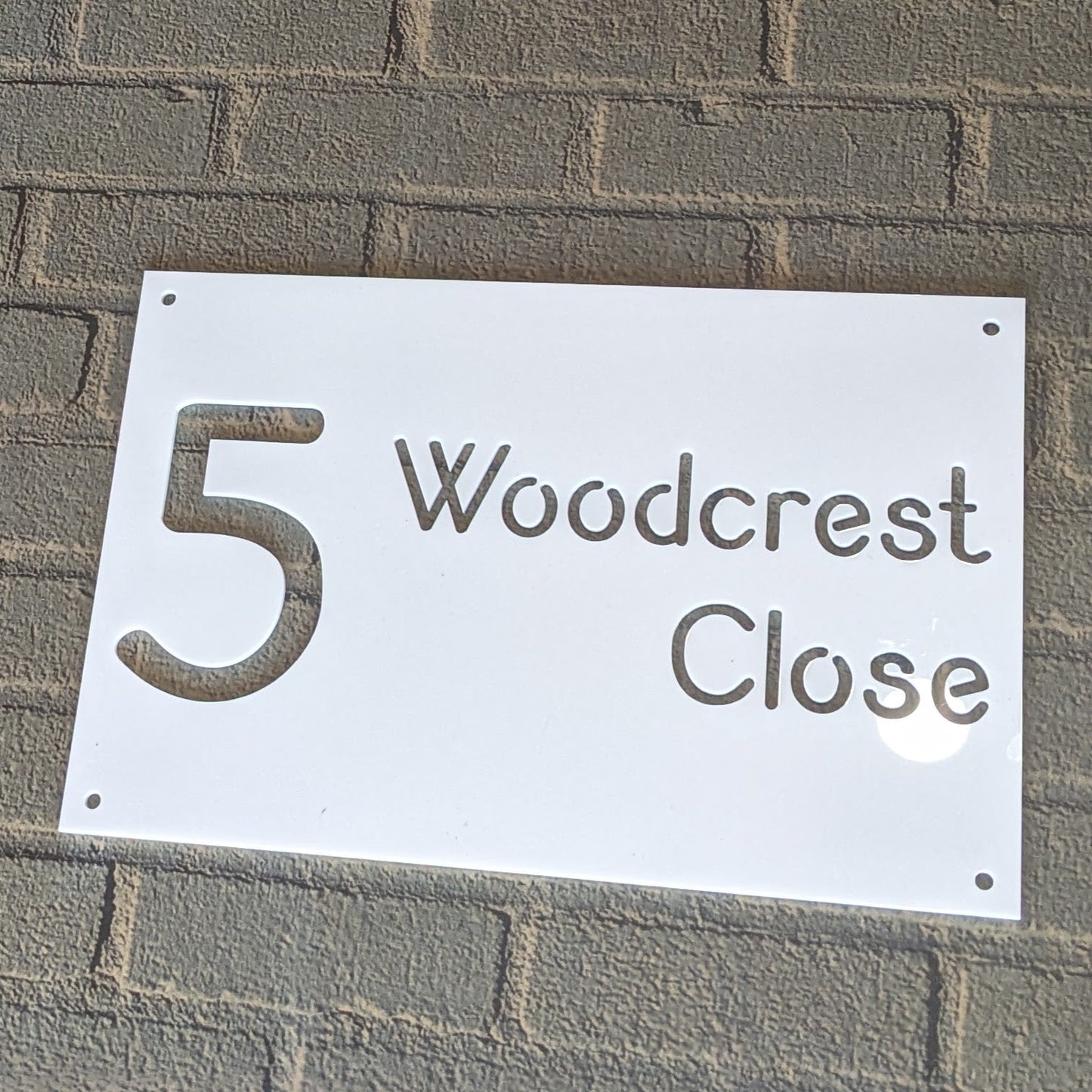 House number sign '5 Woodcrest Close' on a brick wall