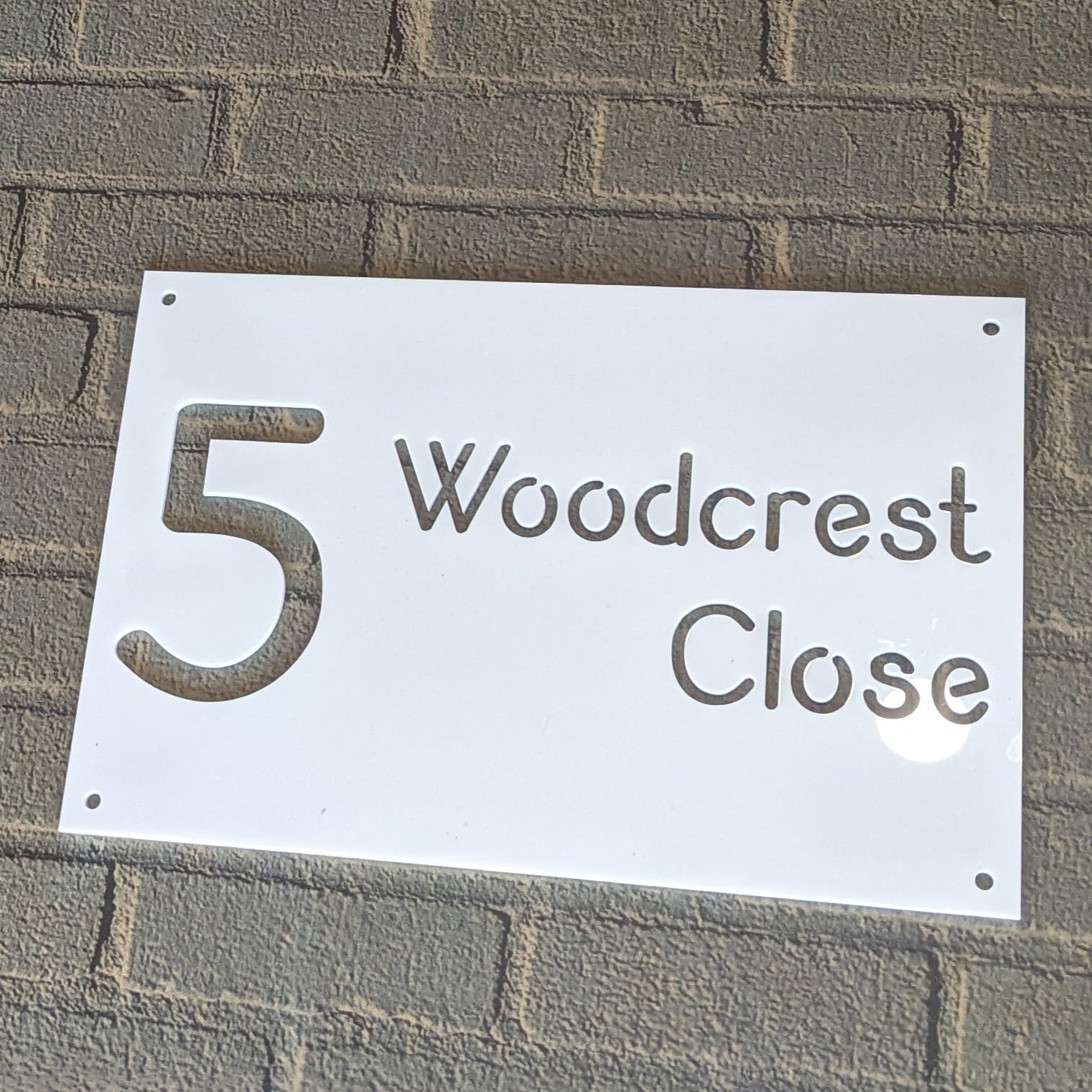 House number sign '5 Woodcrest Close' on a brick wall