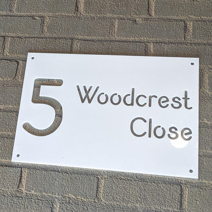 House number sign '5 Woodcrest Close' on a brick wall